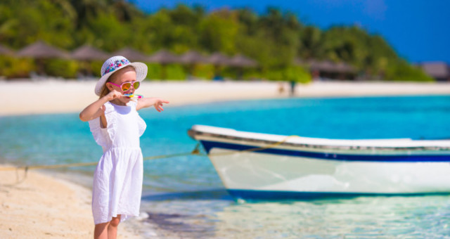 Cute little girl in hat at beach during summer vacation