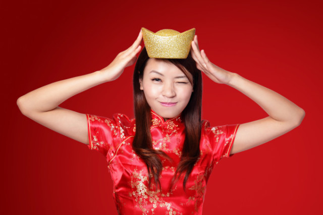 happy chinese new year. smiling asian woman showing gold for lucky. chinese mean get rich and happy