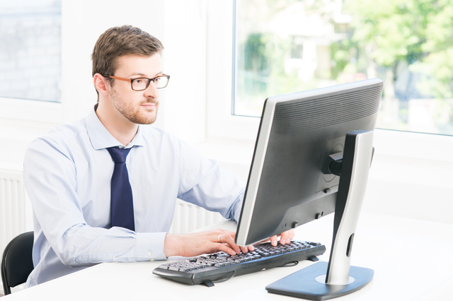 Young and confident businessman working in a modern office. Business man using computer.