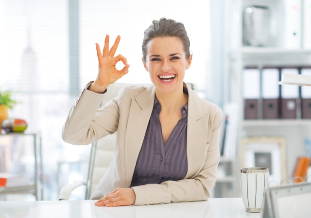 Portrait of smiling business woman showing ok gesture in office