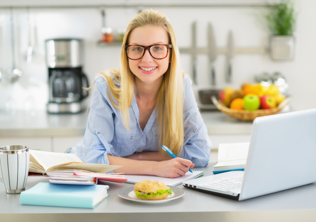 Portrait of smiling young woman studying in kitchen